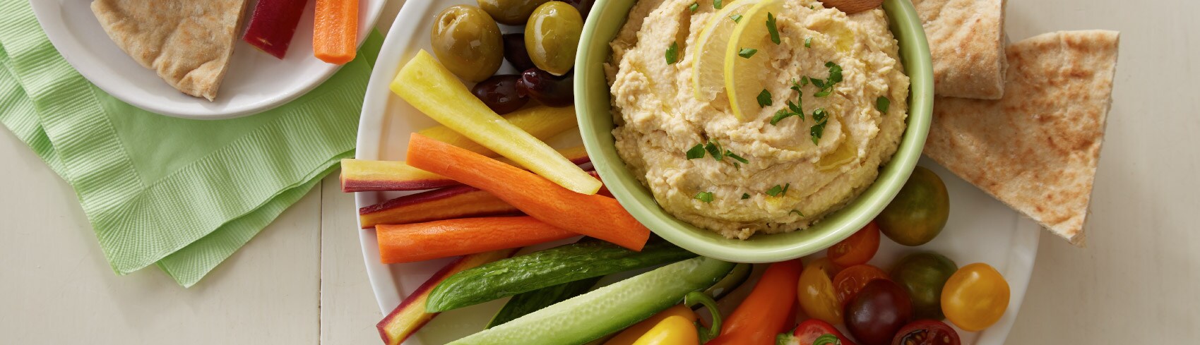 Colorful vegetables and pita chips around a bowl of hummus Colorful vegetables and pita chips around a bowl of hummus