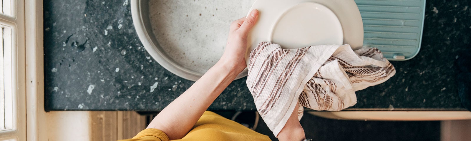 A pair of hands drying dishes