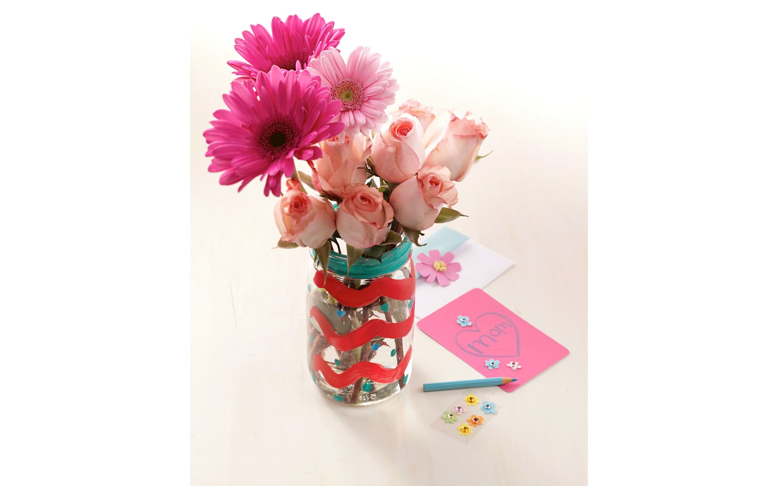 Decorated with pink ribbon around a mason jar filled with roses