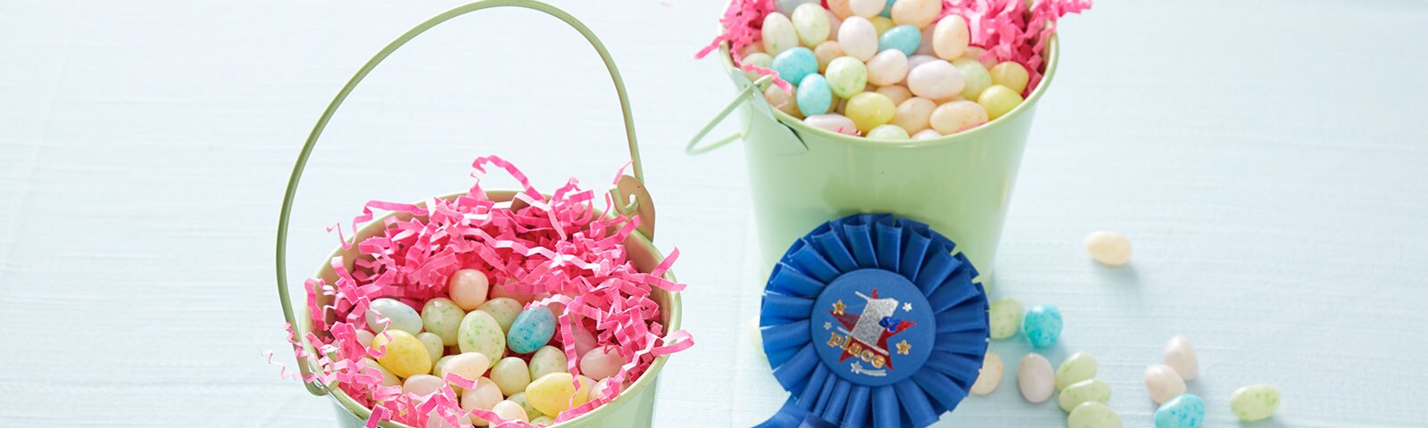 Green baskets filled with jelly beans and pink crinkle paper with a blue "first place winner" ribbon on the side Green baskets filled with jelly beans and pink crinkle paper with a blue "first place winner" ribbon on the side